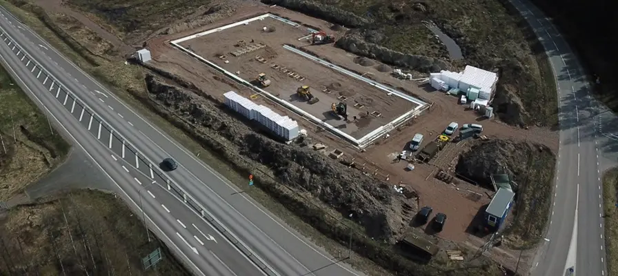En drönarbild över byggnation av Hova Rörledningsaffärs nya lokaler, samt två vägar. 